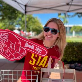 student holding foam finger in quad